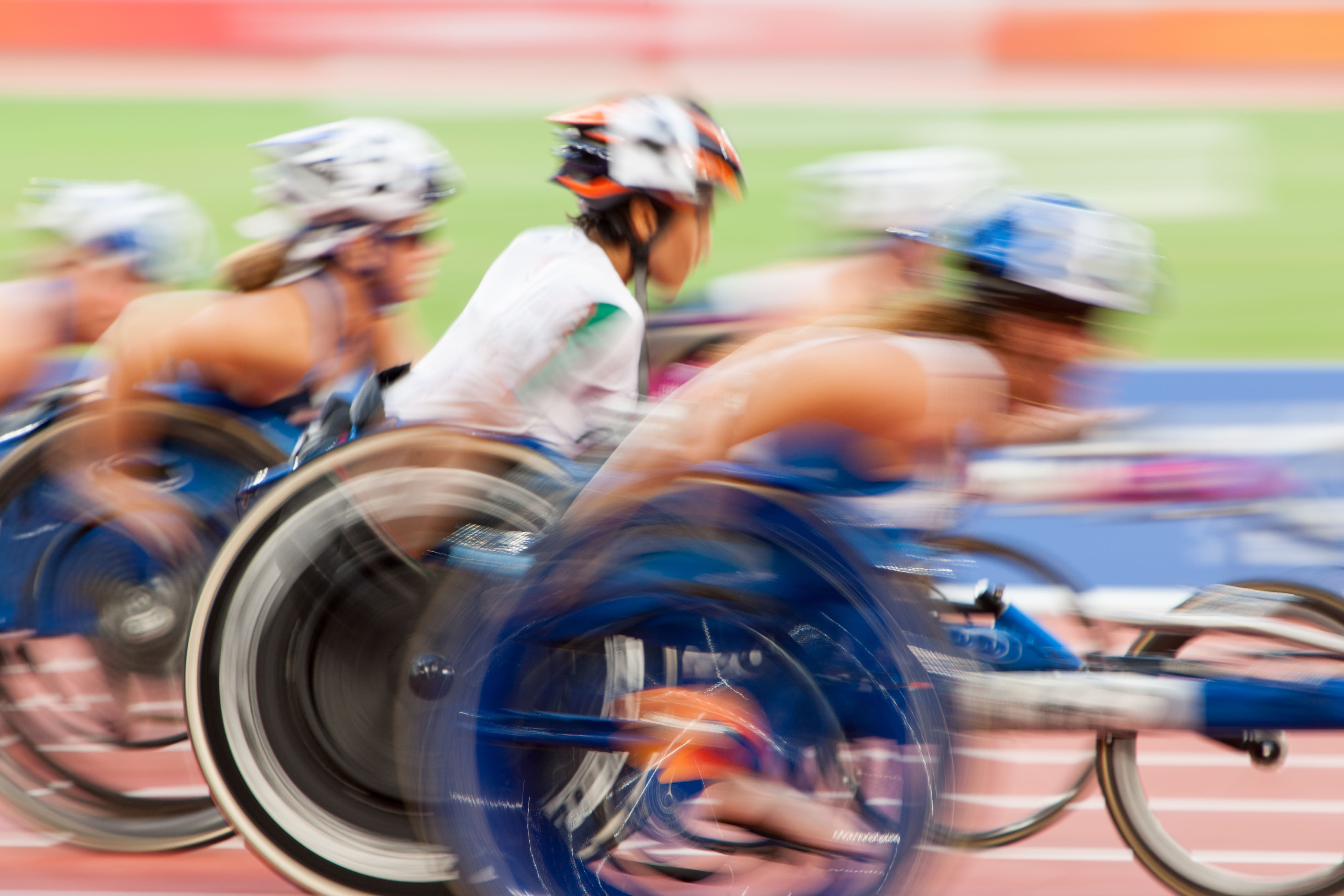 Foto sfocata di atleti alle Paralimpiadi su handbike in una pista di atletica