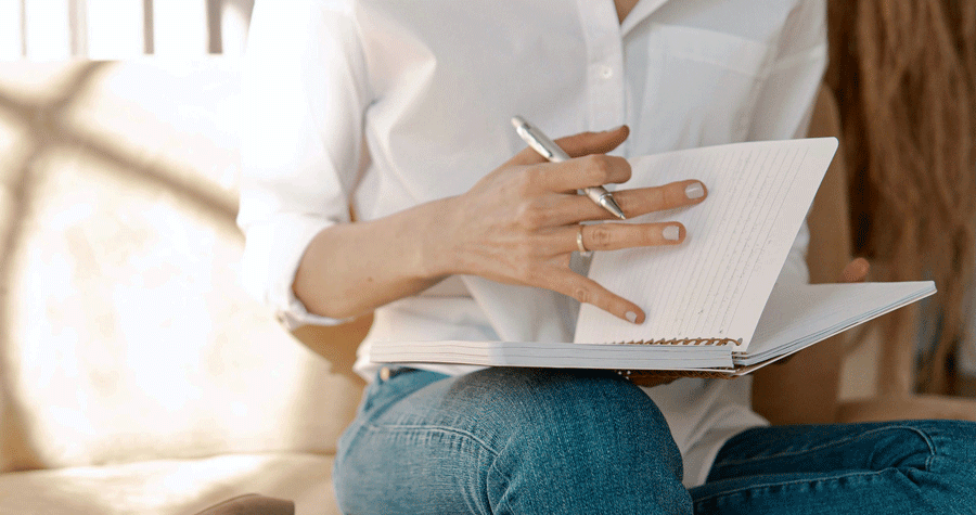 Due mani femminili con una penna in mano che sfogliano un quaderno