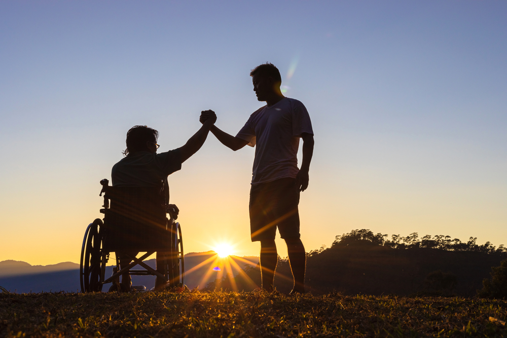 Una persona con disabilità batte il cinque a una persona in piedi