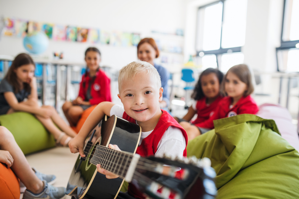 Un bambino suona con la chitarra delle canzoni sulla disabilità